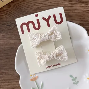 Dettaglio di fermagli per capelli in pizzo beige con motivi traforati su cartoncino