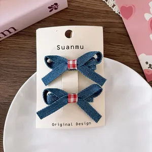 Detail of blue denim bow hair clips with red checkered centers on elegant packaging