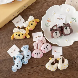Flat lay of colorful plush cartoon animal hair ties with embroidery on wood background