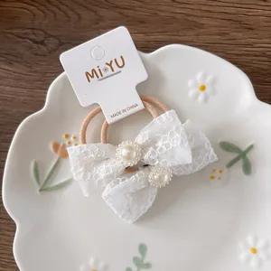 Dettaglio di due elastici per capelli in pizzo bianco con perle su cartoncino
