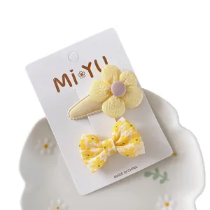 Set aus süßen gelben Stoff-Haarclips mit Blumen und Schleifen für Mädchen auf Karte