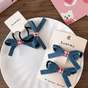 Close-up of blue denim bow hair clips and elastic ties with red gingham accents