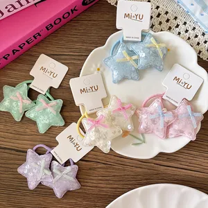 Détail de cinq paires d'élastiques à cheveux étoiles à paillettes aux tons macarons