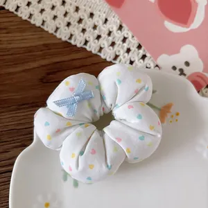 Vista dettagliata di un elastico per capelli bianco con fiocco blu su un piatto decorativo