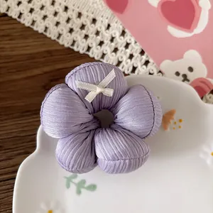 Dettaglio di un elastico a fiori viola con fiocco bianco su un piatto a nuvola