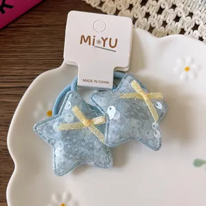 Détail d'élastiques étoiles à paillettes bleu clair avec nœuds jaunes sur plateau blanc