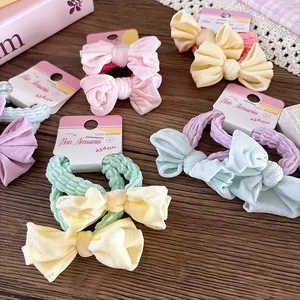 Détail de chouchous à nœuds colorés sur carte blanche avec tissu texturé de qualité