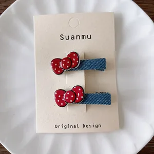 Detail view of denim fabric hair clips with red polka dot bows on a display card