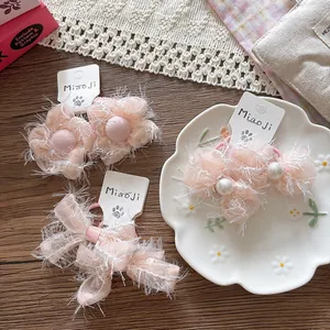 Detail of pink lace flower hair clips with soft fringes and pearl accents on card