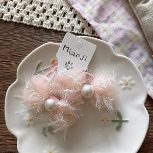Pink chiffon bow hair tie with pearls and feathers on a ceramic petal plate