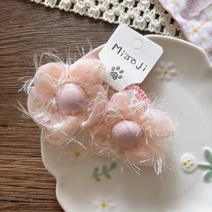 Macro shot of light pink fuzzy flower hair tie with mesh fabric petals on white plate