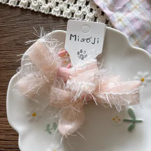 Detail of pink mesh bow hair clips with plush edges on a decorative ceramic plate
