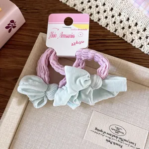 Détail d'un lot de 2 élastiques à cheveux avec nœud vert menthe et cordon rose sur dentelle
