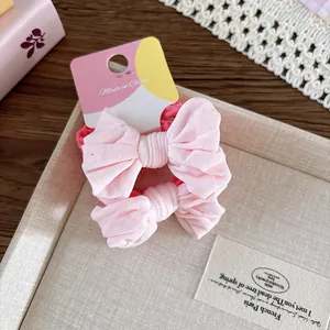 Détail de chouchous à nœuds en tissu rose présentés sur un plateau décoratif doux