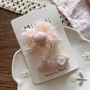 Detailed view of sweet pink mesh flower hair clip with tassels and checkered fabric base