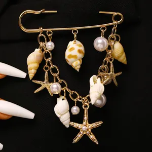 Vue détaillée de la broche dorée avec pendentifs étoiles de mer, coquillages et perles.