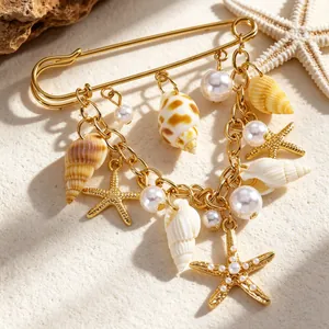 Vue détaillée d'une broche de plage avec étoiles de mer dorées, coquillages et perles.