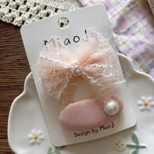 Detail of pink gauze bow hair clip and oval fabric barrette with pearl accents