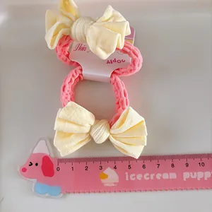 Élastiques à cheveux roses avec de jolis nœuds en tissu jaune sur carte de présentation