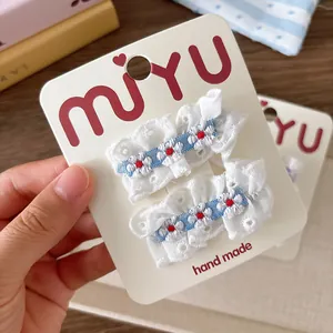 Paire de jolies barrettes en dentelle blanche avec détails floraux bleus sur carte