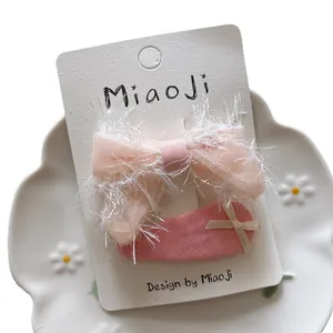 Pink gauze bow hair clip and ribbon elastic tie set on a white display card