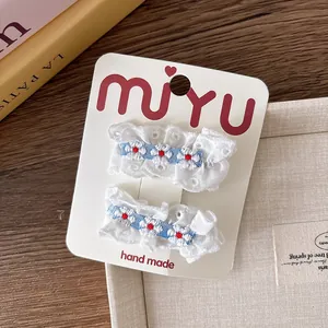 Détail de barrettes en dentelle blanche avec broderie de cœur sur fond en bois