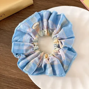 Detalle de coletero de tela a cuadros azules y amarillos con botón decorativo de resina