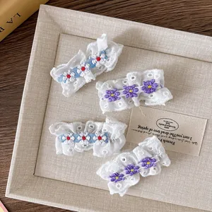Détail de quatre barrettes à cheveux en dentelle brodée florale sur plateau en bois