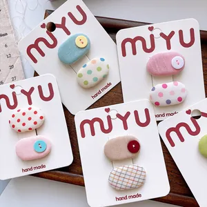 Close-up of handmade cloth-covered oval hair clips with button accents on display cards