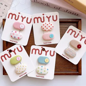 Detailed set of cute polka dot and plaid fabric hair clips in a wooden tray