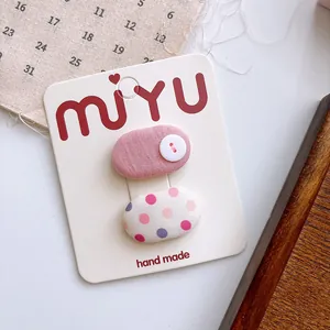 Detail of pink fabric hair clips with dots and button on branded display card