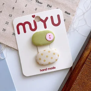 Close-up of handmade cloth hair clips with polka dots and buttons on a display card