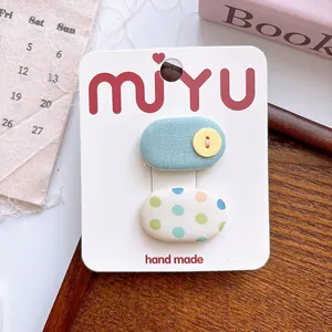Close-up of handmade cloth snap hair clips with polka dots and button on a display card