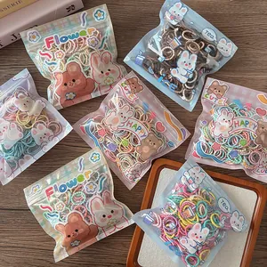 Detailed view of colorful children hair ties in cute cartoon zipper bags on a wooden desk