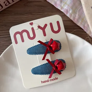 Détail de barrettes en denim faites main avec nœuds en soie rouge et étoiles sur carte