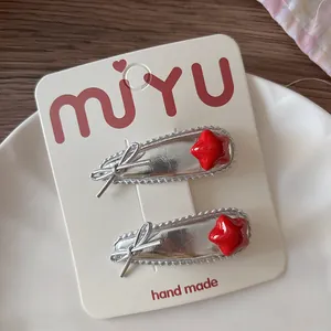 Détail de barrettes pour enfants avec étoiles rouges et nœuds argentés sur carte