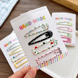 Set of four candy-colored patterned snap hair clips for girls on a handmade card display