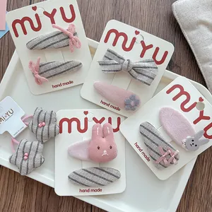Detail of handmade pink and grey striped fabric bow hair clips with bunny and star motifs