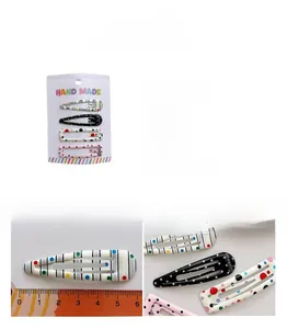 Detail view of four colorful polka dot water drop hair clips with size measurement