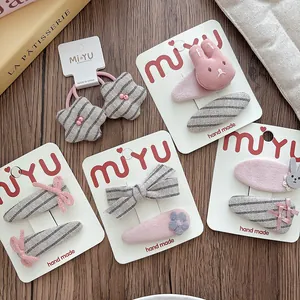 Detail view of pink and grey fabric hair clips and ties with bunny and bow designs.