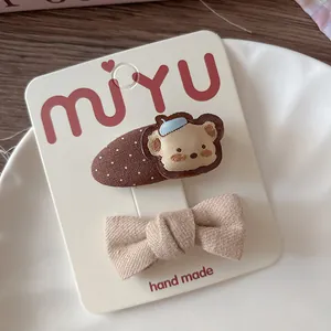 Dettaglio delle mollette per bambini con ricamo a orsetto fatto a mano e fiocco beige