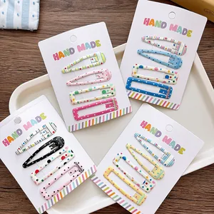 Close-up of four sets of colorful printed snap hair clips for girls on a handmade card