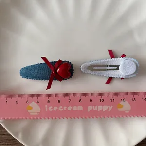 Paire de jolies barrettes BB en denim avec nœuds rouges et cœurs sur plateau blanc