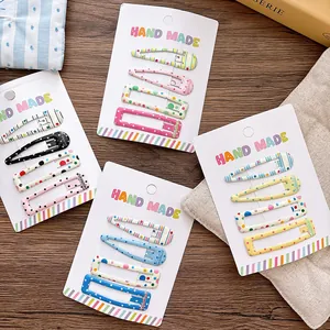 Set of four pastel patterned snap hair clips with polka dots on a white display card