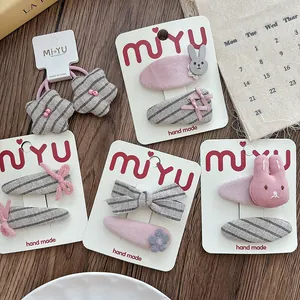 Detail of pink and grey striped fabric hair clips with rabbit and bow designs on card