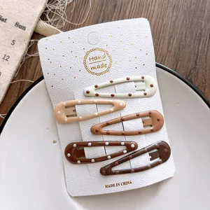 Detailed view of five polka dot BB hair clips in cream and brown tones on card