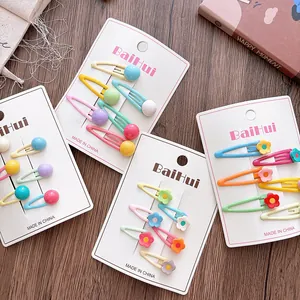 Close-up of colorful flower and ball BB hair clips for girls on white cards