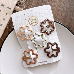 Close-up of five coffee-colored floral BB hair clips on a handmade display card