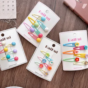 Detail of candy-colored flower hair clips set on white card with a wooden background