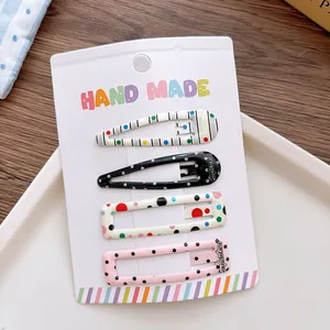 Detail view of 5cm printed snap hair clips on handmade card with colorful patterns